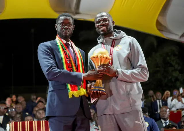 Le président du Sénégal Bassirou Diomaye Faye et le capitaine de l'équipe nationale Khalidou Koulibaly célèbrent la victoire du Sénégal en Coupe d'Afrique des Nations 2025 avec le trophée