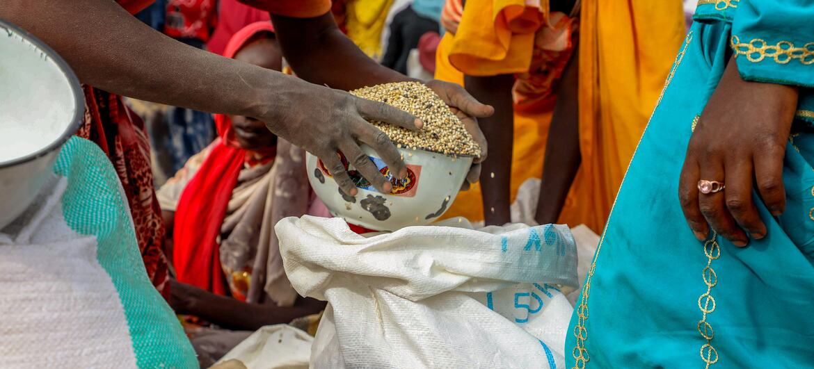 Un membre du personnel du PAM verse du sorgho dans un bol lors d'une distribution d'aide alimentaire à Adré, au Tchad.