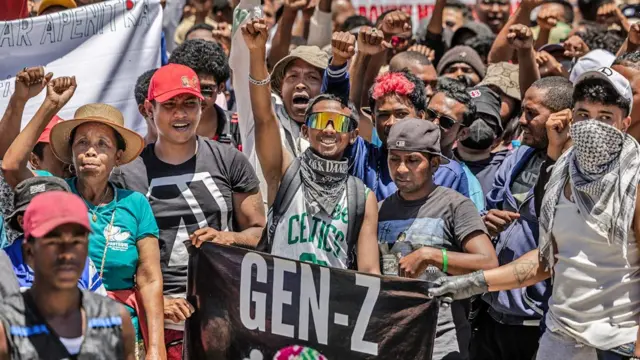 Un groupe de manifestants, dont certains brandissent une banderole « Génération Z », lèvent les poings en l'air.