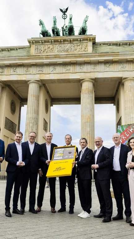 Christian Prudhomme et les responsables de la candidature de Berlin pour accueillir le Tour de France en 2029 posent devant la Porte de Brandebourg, le 29 juillet 2027. (CHRISTOPH SOEDER / AFP)